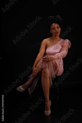 Wallpaper Mural Low key portrait of young curly woman in pink dress sitting in a chair Torontodigital.ca