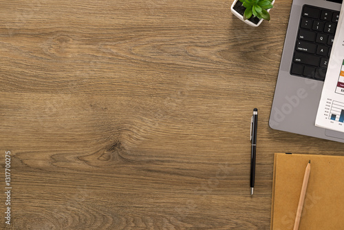 Obraz na płótnie Top view of a wooden office desk with a laptop, financial documents and notebook. A clean and organized workspace for productivity and planning w salonie