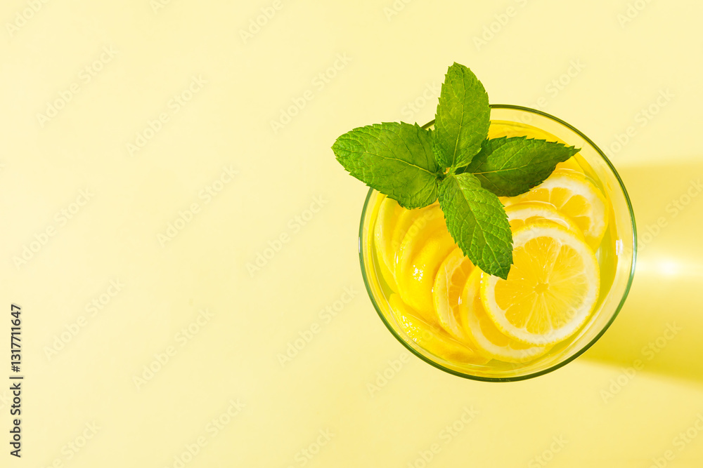 Glass of lemonade with mint against yellow background.