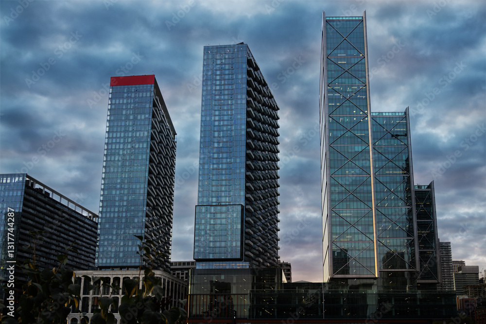 Toronto condo towers against a dramatic cloudy sky. Modern glass architecture and urban skyline, ideal for real estate, architecture design, and cityscape visuals. Captures the essence of city living.