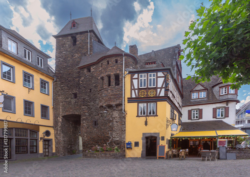 Stone city gate, half-timbered house, and outdoor cafe on a square in Cochem, Germany