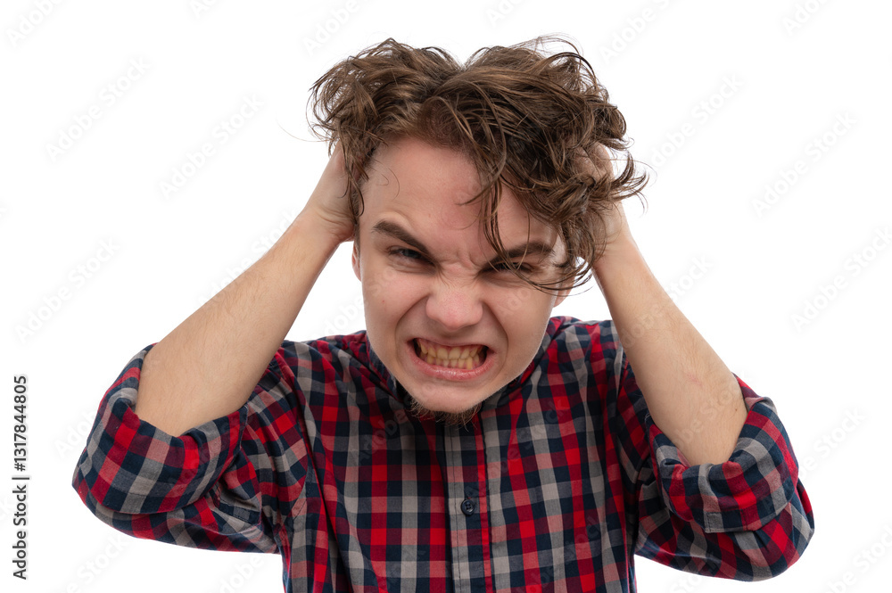 A young man with curly hair showing frustration by holding his head and grimacing against a white background. A young man with curly hair showing frustration by holding his head and grimacing against a white background.
