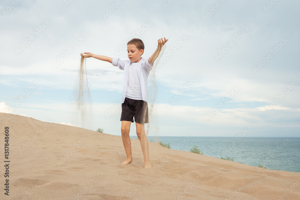 Boy playing with sand on beach dune overlooking ocean under cloudy sky summer vacation childhood freedom nature exploration Boy playing with sand on beach dune overlooking ocean under cloudy sky summer vacation childhood freedom nature exploration