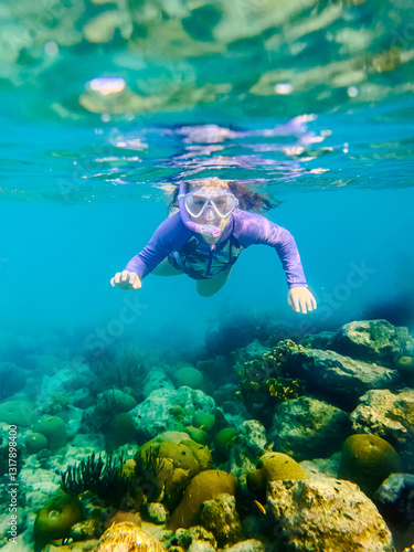 girl snorkeling through a coral reef  in the Caribbean ocean