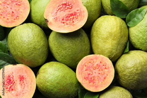 Fresh cut and whole guava fruits as background, top view
