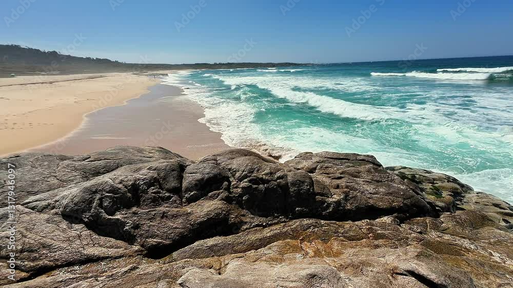 A stunningly beautiful beach scene with vibrant turquoise waves crashing dramatically against the rocky shore A stunningly beautiful beach scene with vibrant turquoise waves crashing dramatically against the rocky shore