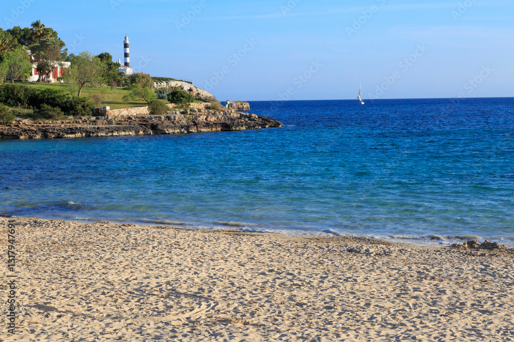 Europe, Spain, Balearic Islands, Mallorca. Porto Colom. lighthouse, children play on beach. 2017-04-16