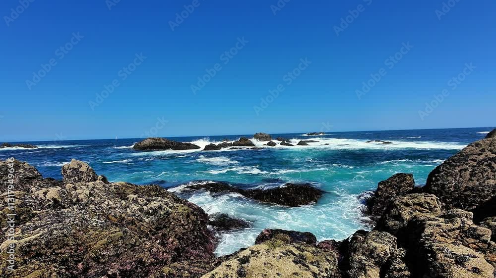 A stunning coastal scene with waves crashing on rocks under a blue sky, perfect for beach exploration and relaxation A stunning coastal scene with waves crashing on rocks under a blue sky, perfect for beach exploration and relaxation