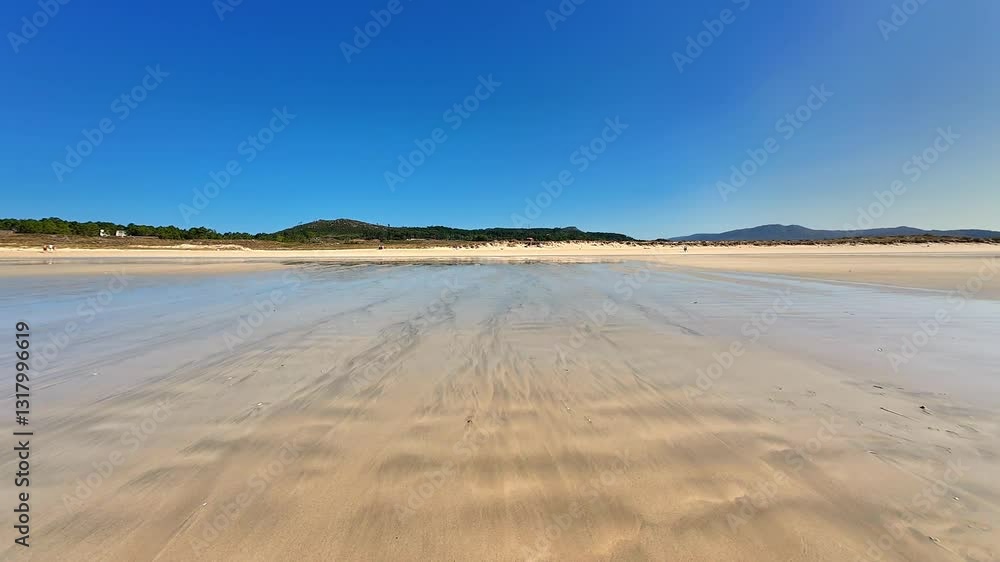 A tranquil beach scene features a sandy shore and a vibrant blue sky reflected on the waters surface A tranquil beach scene features a sandy shore and a vibrant blue sky reflected on the waters surface