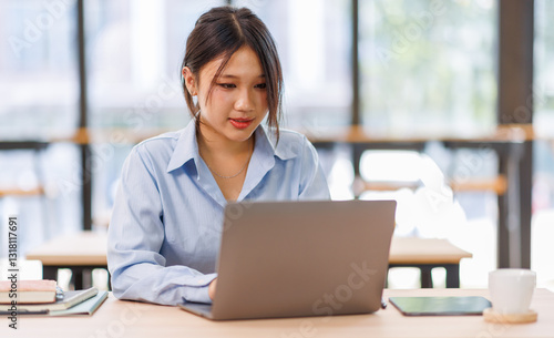 Young asian female entrepreneur working on a laptop at business meeting in a corporate workplace.
