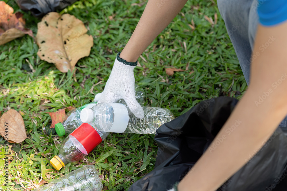 Fototapeta premium Volunteer collecting plastic bottles during an environmental cleanup