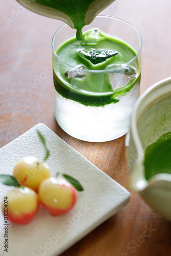 fresh matcha tea, green tea pouring on a glass of coconut water and colorful peach fruit shape Plating balls, Thailand style dessert on wooden table.