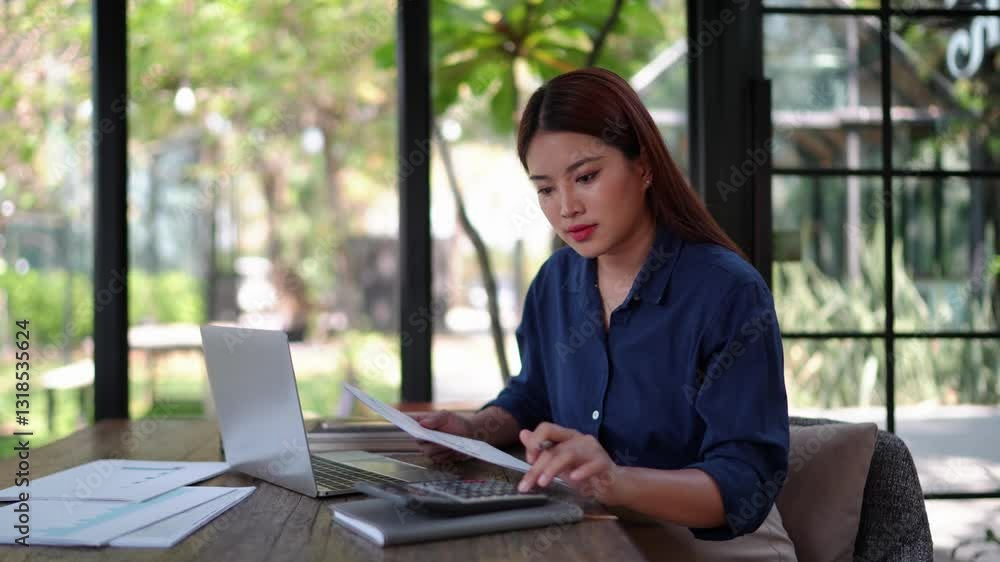 Businesswoman calculating company budget using a calculator and documents at a natural-themed workspace with a laptop. Businesswoman calculating company budget using a calculator and documents at a natural-themed workspace with a laptop.