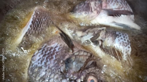 Tilapia fish is fried in boiling oil in a skillet