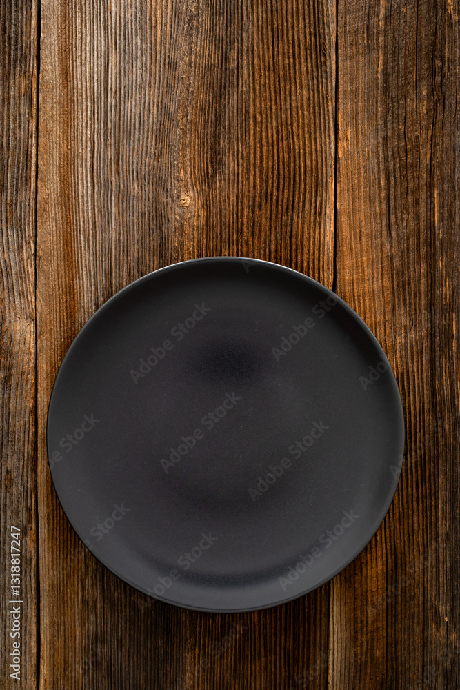 Empty black plate on wooden rustic table Empty black plate on wooden rustic table
