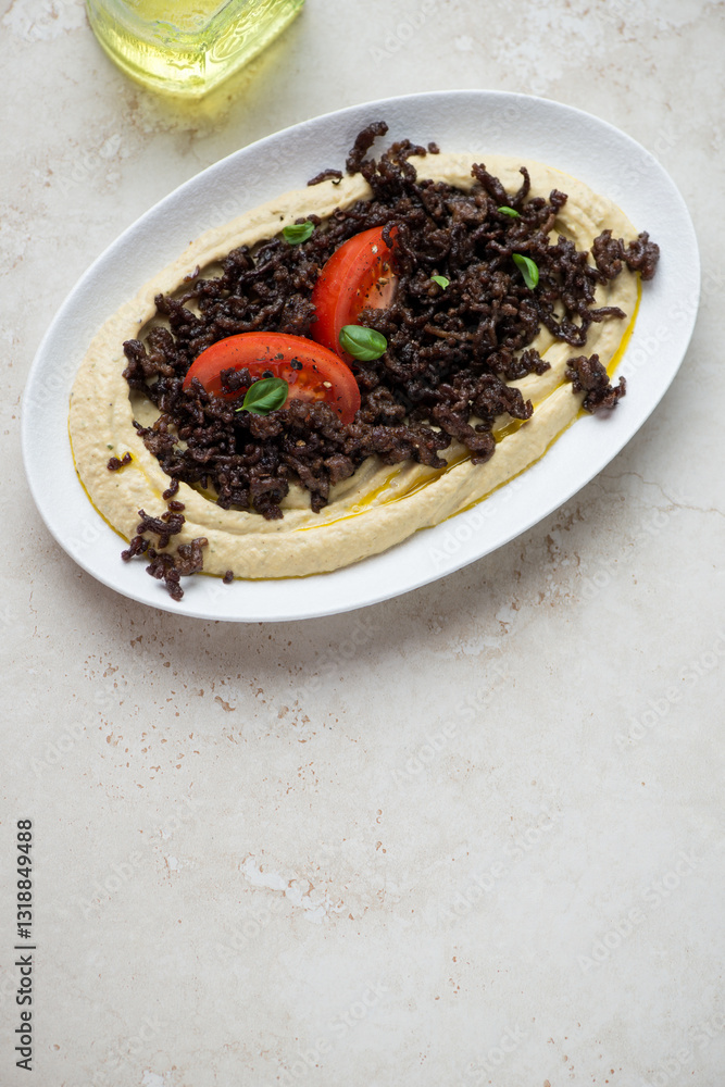 Plate with hummus and roasted ground beef meat, vertical shot on a light-beige stone background, high angle view, copy space Plate with hummus and roasted ground beef meat, vertical shot on a light-beige stone background, high angle view, copy space