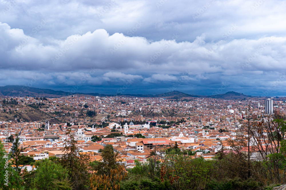 Fototapeta premium Dramatic Cloudy Sky Over Sucre Bolivia Panoramic View Of The White City With Its Traditional Rooftops And Historic Landmarks Under A Stormy Horizon