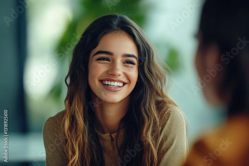 Wallpaper Mural A young woman with long, wavy hair smiles warmly while engaging in conversation at a modern caf?, with greenery softly blurred in the background Torontodigital.ca