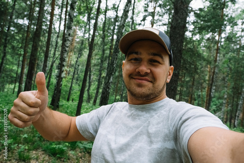 Man in a cap smiling and taking a selfie in forest in summer
