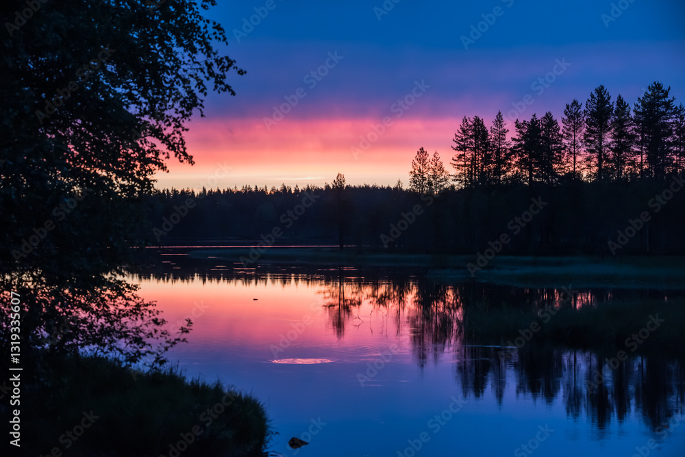 Reflection of sunset colours on the surface of a lake in the forests of eastern Finland on a summer night Reflection of sunset colours on the surface of a lake in the forests of eastern Finland on a summer night