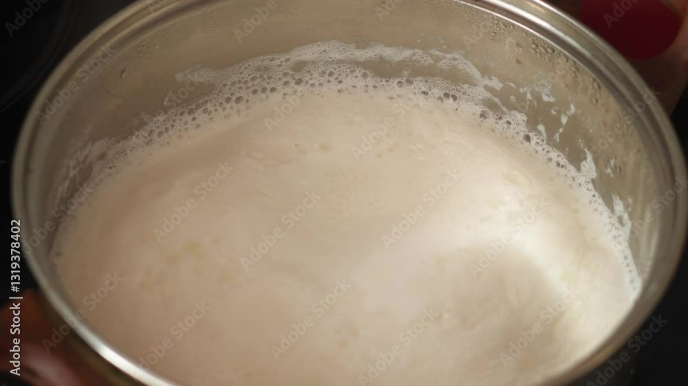 close up boiling milk in a saucepan stirred with a metal spoon, boiling milk macro close up boiling milk in a saucepan stirred with a metal spoon, boiling milk macro