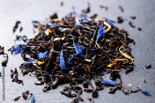 Earl grey loose leaf tea blend with cornflower and orange blossom petals on dark marble board. Close up.