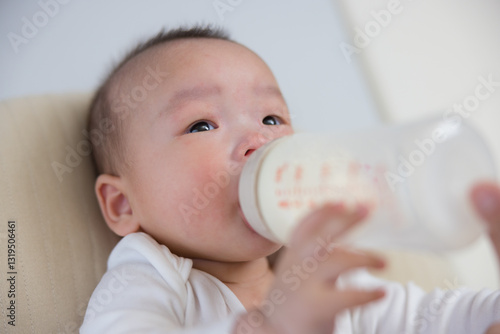 Cute baby holding bottle while drinking milk