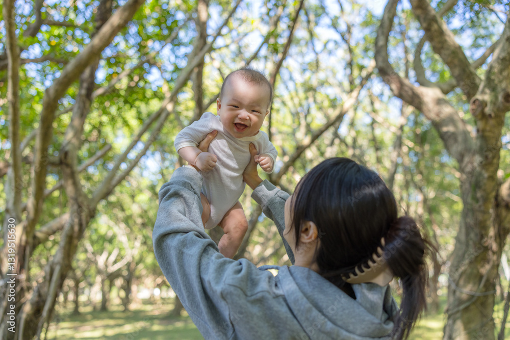 Cheerful mom raising adorable baby in park Cheerful mom raising adorable baby in park