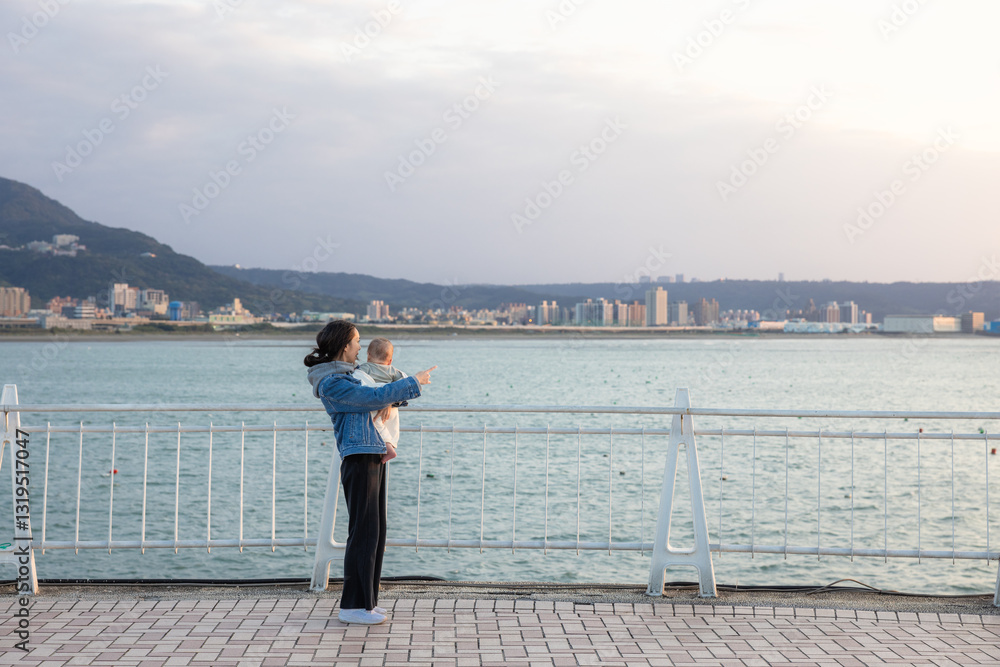 Mother holding baby while looking at ocean view