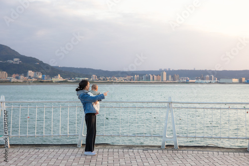 Obraz na płótnie Mother holding baby while looking at ocean view w salonie