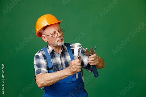 Obraz na płótnie Studio photo of a man worker holding tools isolated on green background w salonie