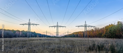 High voltage power lines over a field at sunset