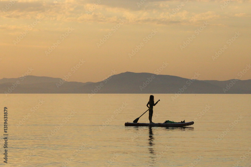 Naklejka premium Silhouette of an woman on a surfboard at sunset