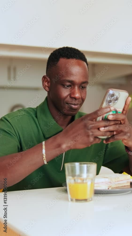 Vertical video, Young Man Browsing Phone at Kitchen Table Vertical video, Young Man Browsing Phone at Kitchen Table