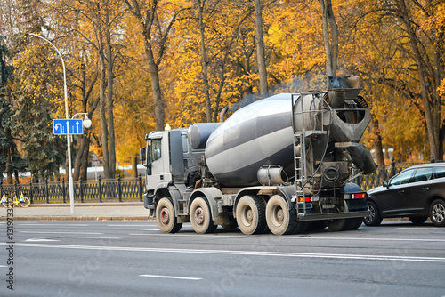 Obraz na płótnie Cement mixer truck driving on an urban road in autumn, industrial transportation and construction logistics in city environment. Heavy duty concrete mixing truck moving through city streets. w salonie