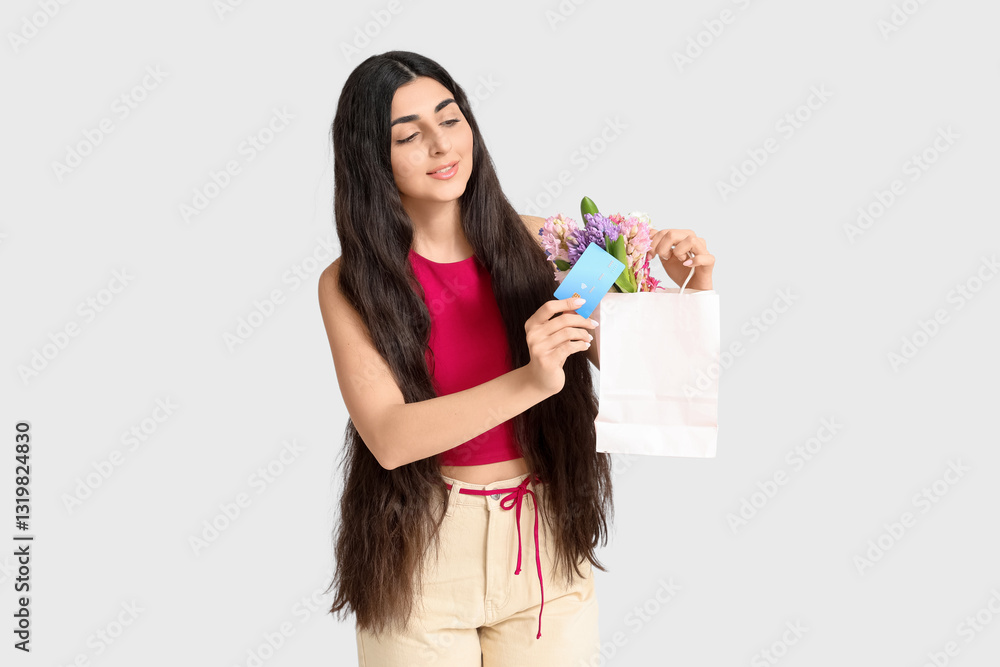 Young woman holding paper bag with hyacinth flowers and credit card on white background Young woman holding paper bag with hyacinth flowers and credit card on white background