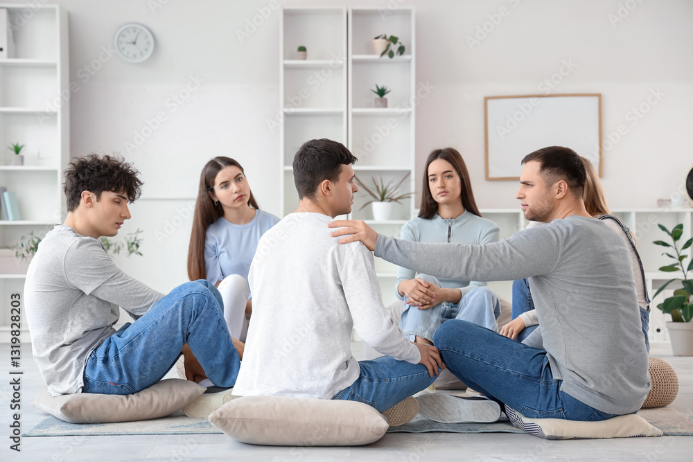 Male psychologist calming young man at group therapy session Male psychologist calming young man at group therapy session