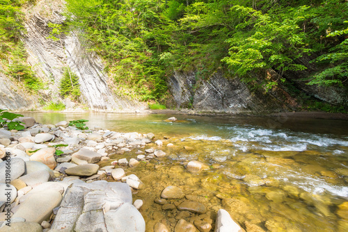 mountain river with stones on the shore. transparent water. scenic landscape with forest on the rocky mountain slope. nature scenery on a sunny summer day. travel background