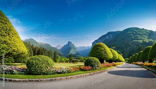 a tranquil road meanders through vibrant trees and well kept gardens inviting visitors to explore the breathtaking mountainous landscape that looms ahead