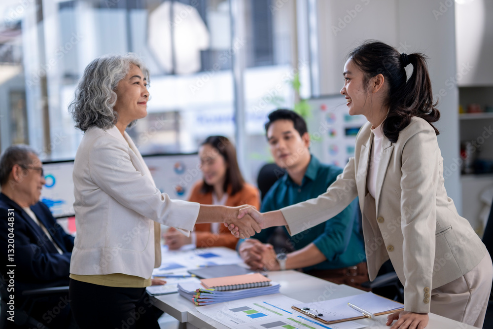 A woman shakes hands with another woman in a business setting