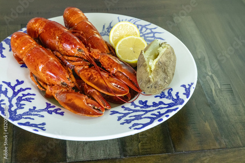 Whole lobsters from Maine on a nautical dish with a baked potato photo