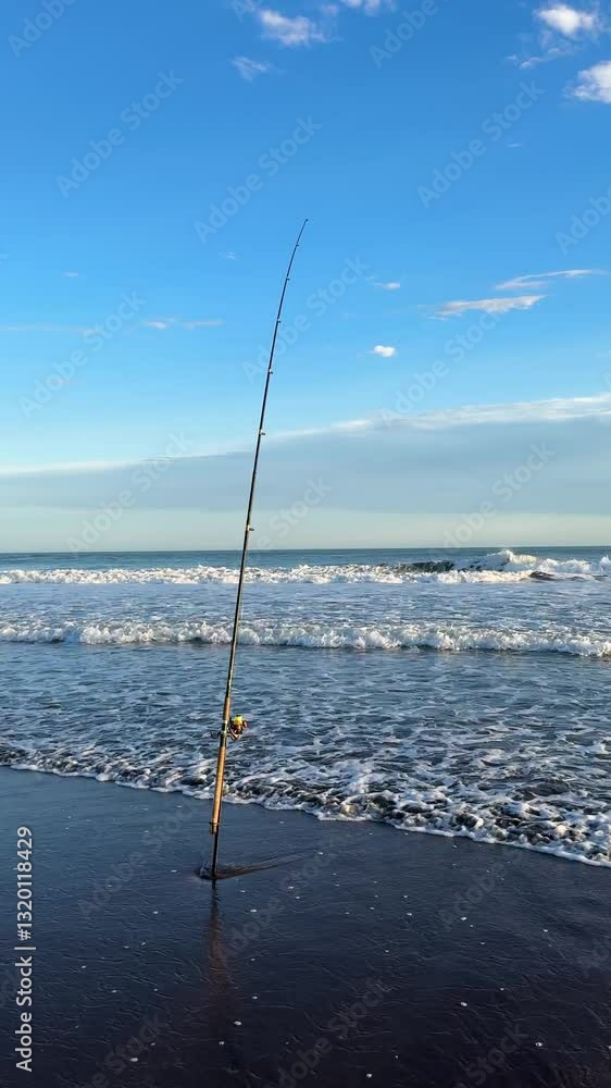 Fishing Rod On The Beach - Fishing In The Sea In The Early Morning. - vertical shot Fishing Rod On The Beach - Fishing In The Sea In The Early Morning. - vertical shot