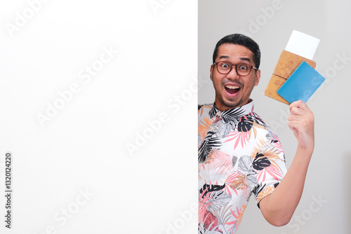 A tourist peeking from behind a wall holding travel document, ticket and passport with excited expression photo