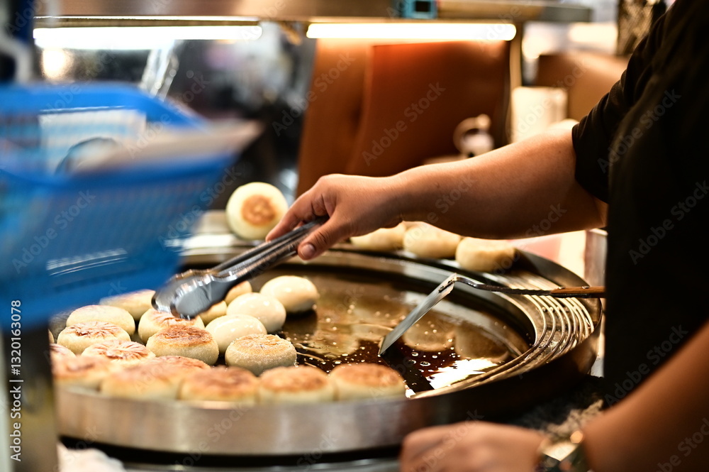 A night market vendor skillfully prepares stuffed pancakes on a hot griddle. The golden-brown crust glistens under the light as steam rises, filling the air with a mouthwatering aroma.