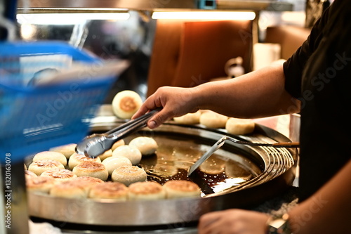 Obraz na płótnie A night market vendor skillfully prepares stuffed pancakes on a hot griddle. The golden-brown crust glistens under the light as steam rises, filling the air with a mouthwatering aroma. w salonie