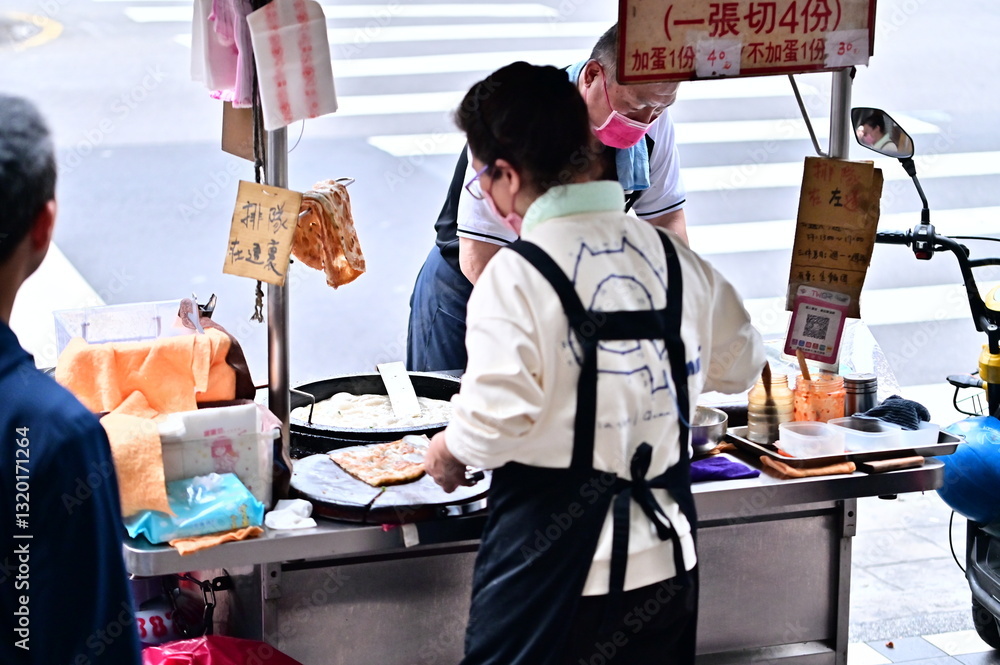 Taiwan - Feb 16, 2025: Steam rises as scallion pancakes sizzle in the pan, while a vendor swiftly prepares each order. The comforting sight and smell are a familiar part of Taiwan’s street life.