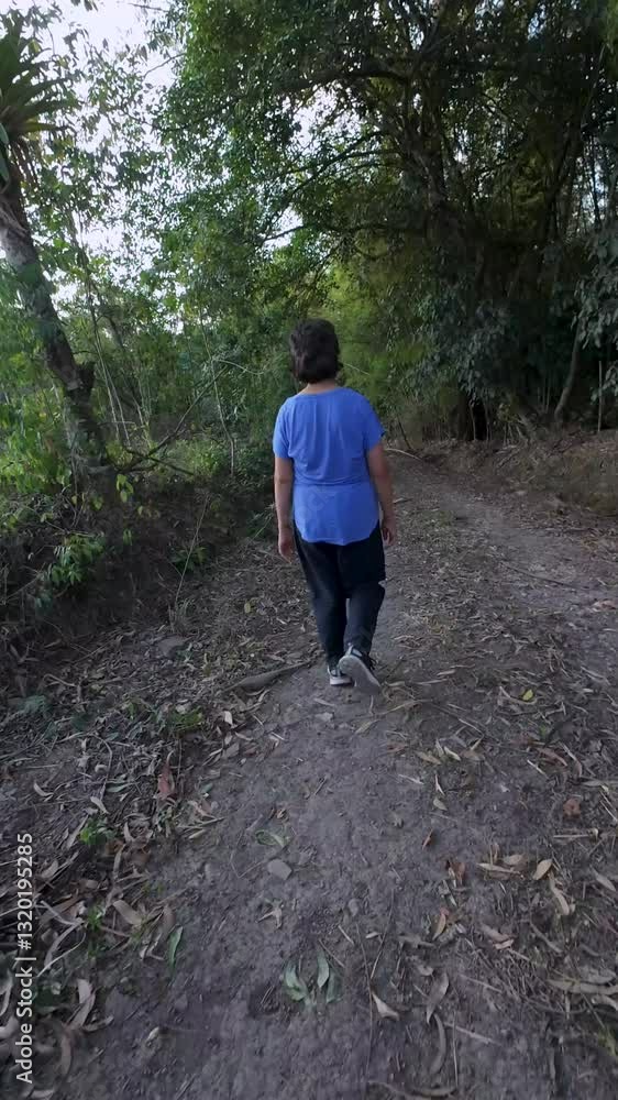 Senior pensioner woman walking on a gravel path in a forest