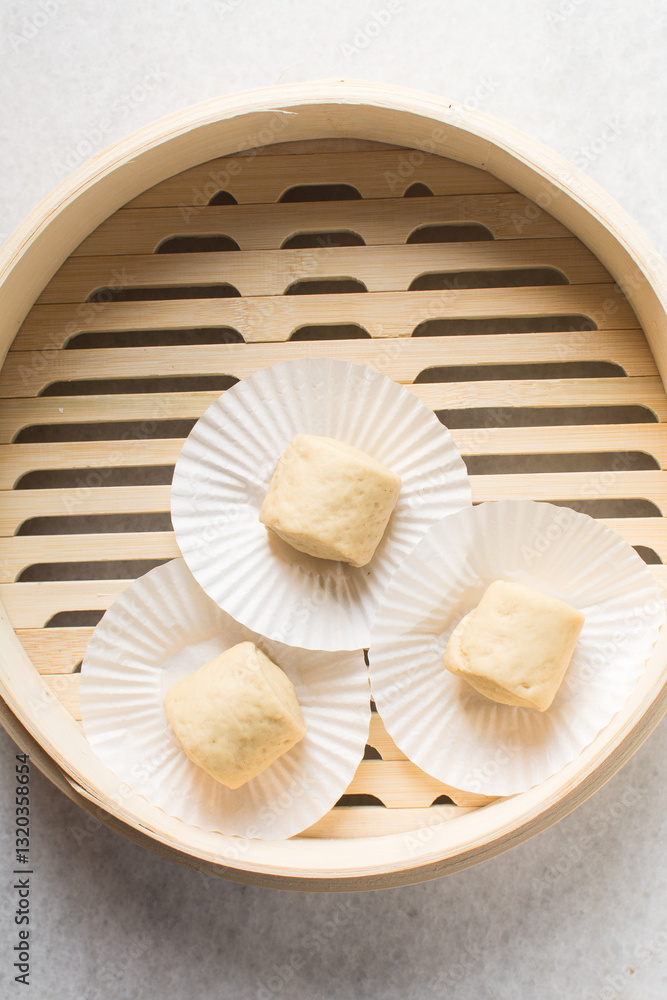 Overhead view of steamed bun dough in a steamer basket, top view of mantou dough in a bamboo steamer, process of making steamed milk buns Overhead view of steamed bun dough in a steamer basket, top view of mantou dough in a bamboo steamer, process of making steamed milk buns