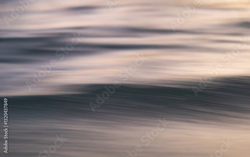 Abstract photograph of the ocean's surface taken from a moving boat. The motion blur creates a dreamy, ethereal effect, with the water's texture and subtle color variations highlighted.