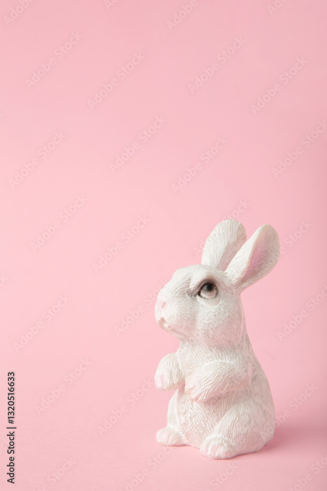 Obraz premium White ceramic rabbit on pink background. Vertical photo